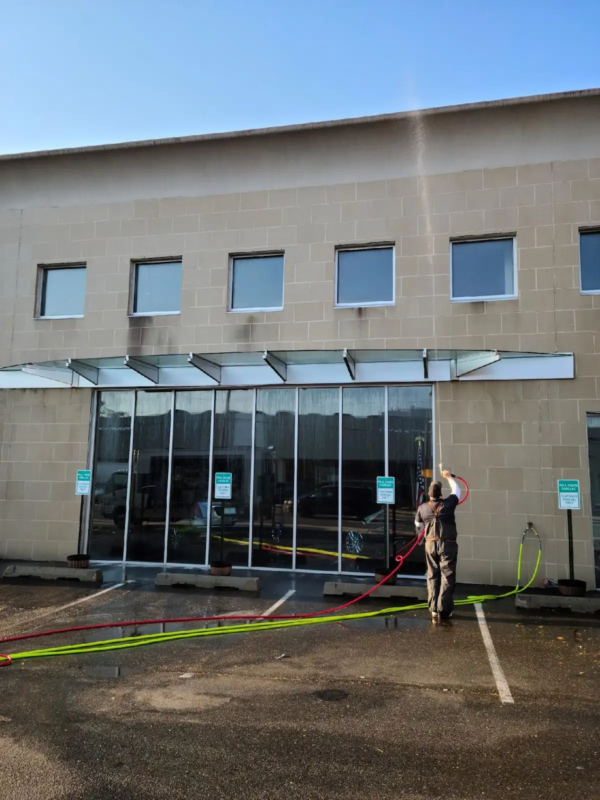 Kevin pressure washing Paul Conte Cadillac building exterior — commercial power washing Freeport NY by Pressure Wash Long Island