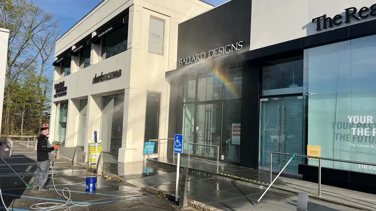 Matthew rinsing Ballard Designs storefront on Miracle Mile — commercial power washing Manhasset NY by Pressure Wash Long Island
