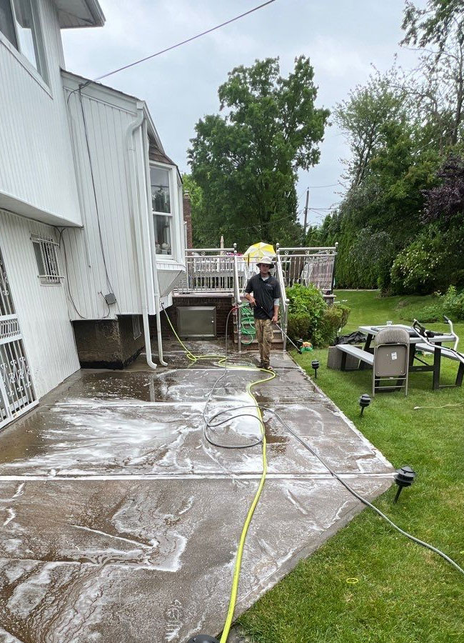 Matthew applying surfactant solution to concrete driveway — pressure washing Long Island NY by Pressure Wash Long Island